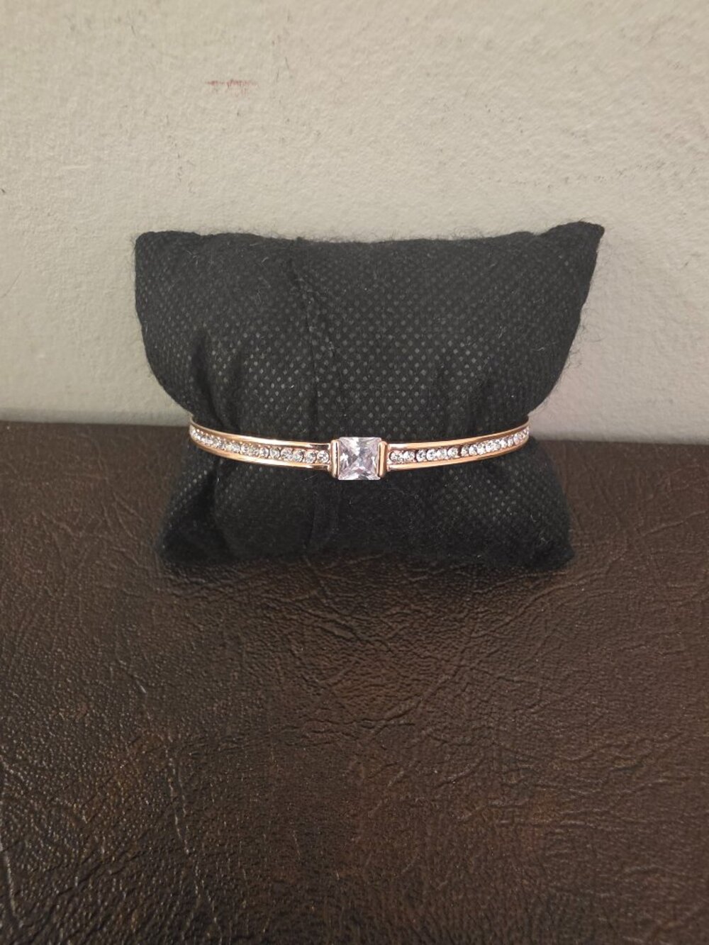 Gold toned bangle bracelet with a central cubic zirconia stone.